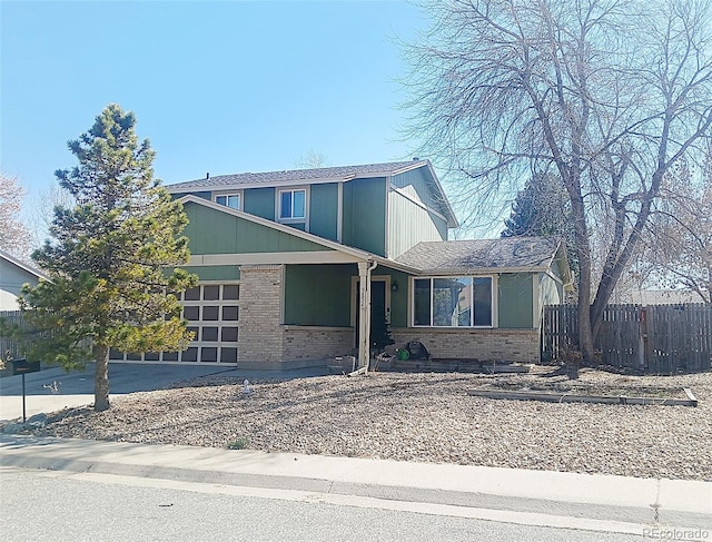 traditional-style home featuring brick siding, concrete driveway, a garage, and fence