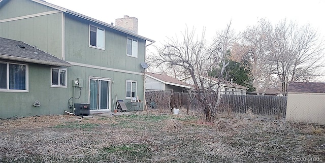 rear view of house with fence, central AC, and a chimney