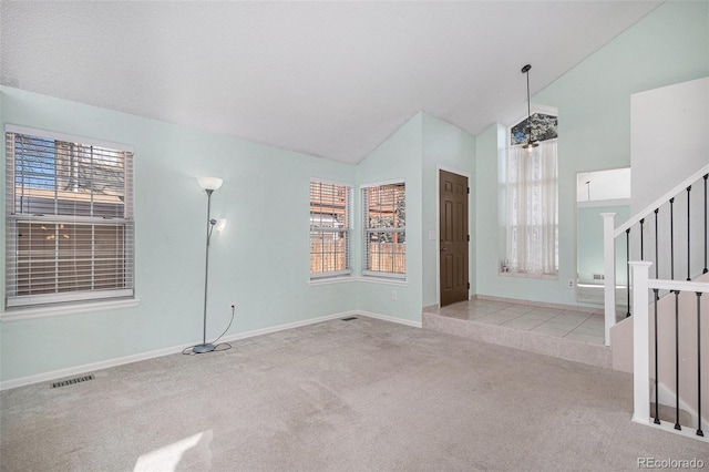 carpeted entrance foyer with stairs, lofted ceiling, visible vents, and baseboards