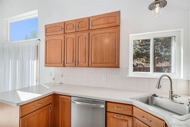 kitchen with dishwasher, light countertops, a sink, and decorative backsplash