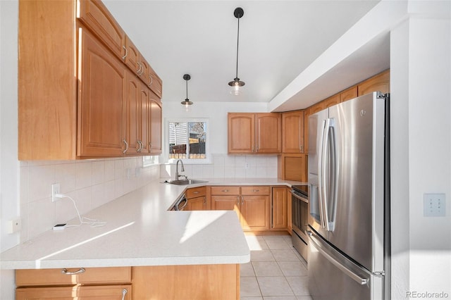 kitchen with a peninsula, a sink, light countertops, appliances with stainless steel finishes, and tasteful backsplash