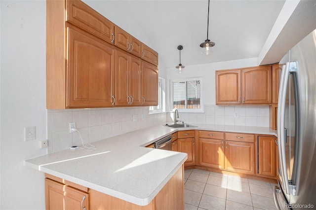 kitchen featuring stainless steel appliances, backsplash, a sink, and a peninsula