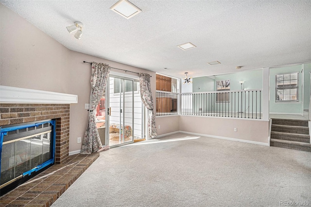 unfurnished living room featuring carpet floors, a fireplace, baseboards, and a textured ceiling