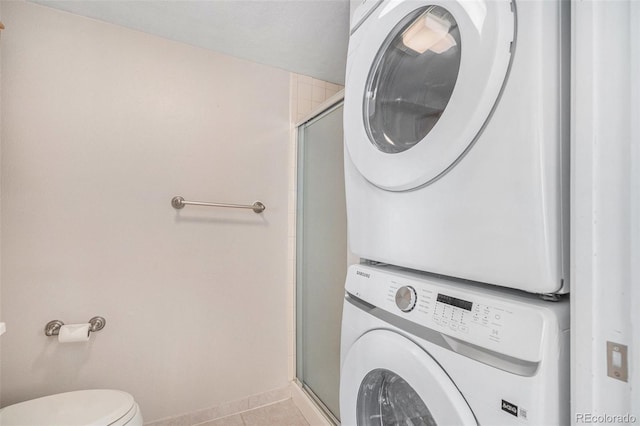 washroom featuring laundry area, tile patterned floors, baseboards, and stacked washer and clothes dryer