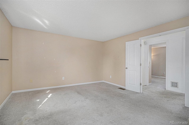 spare room featuring a textured ceiling, carpet flooring, and baseboards