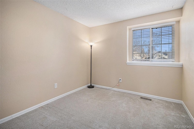 spare room featuring visible vents, a textured ceiling, baseboards, and carpet flooring