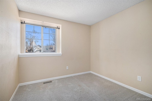 carpeted empty room with visible vents, baseboards, and a textured ceiling