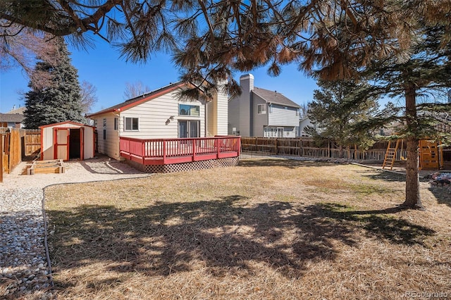 back of house featuring a fenced backyard, a storage unit, a wooden deck, an outdoor structure, and a playground