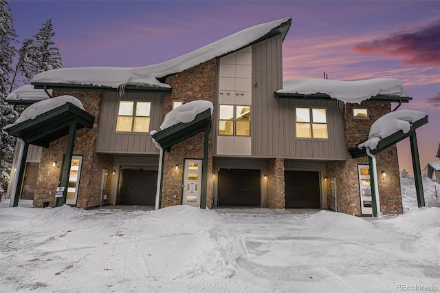 view of front of home featuring board and batten siding, a garage, and stone siding