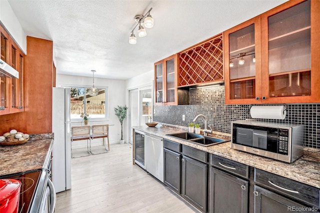 kitchen featuring sink, appliances with stainless steel finishes, light stone countertops, a textured ceiling, and decorative light fixtures