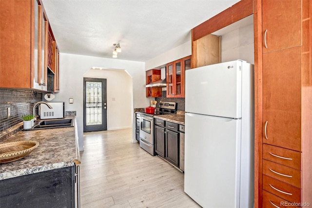 kitchen featuring sink, tasteful backsplash, stainless steel range with electric stovetop, light wood-type flooring, and white fridge