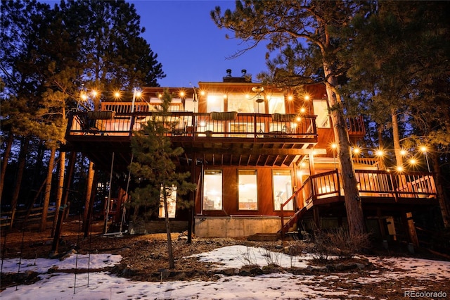 snow covered back of property featuring a wooden deck