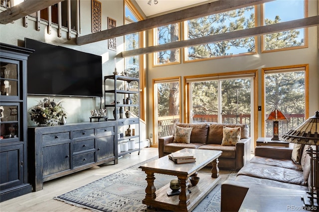 living room featuring light wood-type flooring, baseboard heating, and a high ceiling