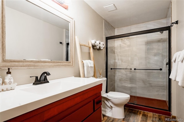 bathroom with an enclosed shower, hardwood / wood-style floors, vanity, and toilet