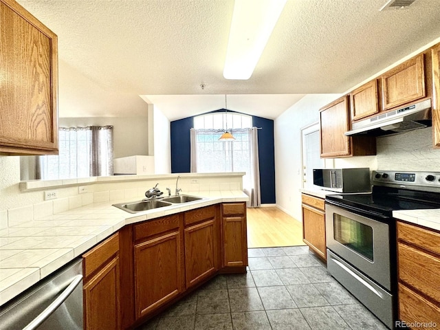 7440 S Blackhawk St Unit 208, Englewood, CO 80112 - kitchen featuring stainless steel appliances, under cabinet range hood, tile countertops, a sink, and healthy amount of natural light