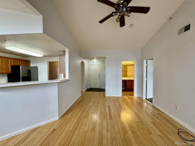 7440 S Blackhawk St Unit 208, Englewood, CO 80112 - unfurnished living room featuring a ceiling fan, arched walkways, baseboards, lofted ceiling, and light wood finished floors