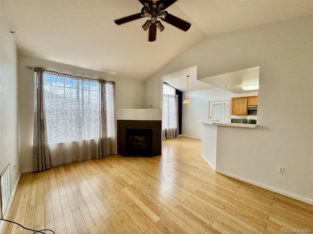7440 S Blackhawk St Unit 208, Englewood, CO 80112 - unfurnished living room with ceiling fan, vaulted ceiling, light wood-style floors, a fireplace, and baseboards