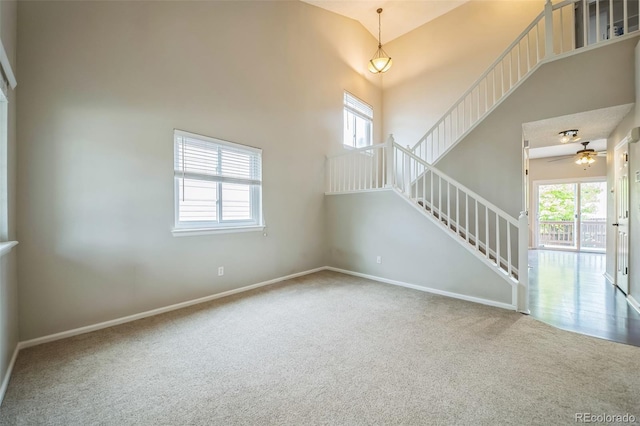 2446 S Gibralter Way, Aurora, CO 80013 - unfurnished living room featuring carpet floors, stairs, ceiling fan, and a towering ceiling