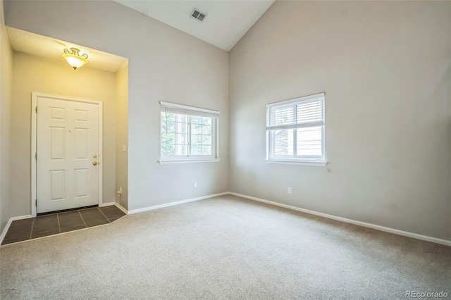 2446 S Gibralter Way, Aurora, CO 80013 - entryway with dark carpet, high vaulted ceiling, and dark tile patterned flooring