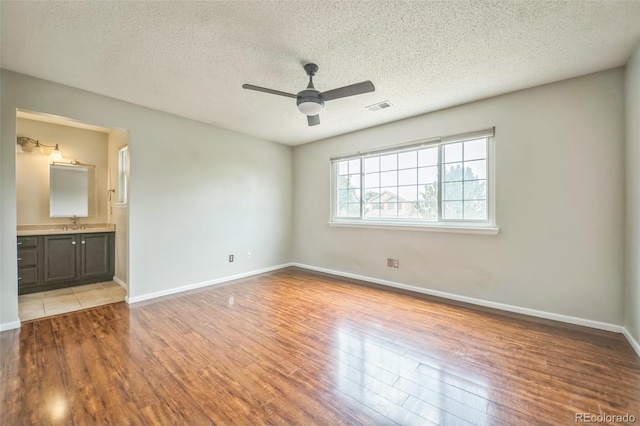 2446 S Gibralter Way, Aurora, CO 80013 - unfurnished bedroom with wood finished floors, a textured ceiling, connected bathroom, and a ceiling fan