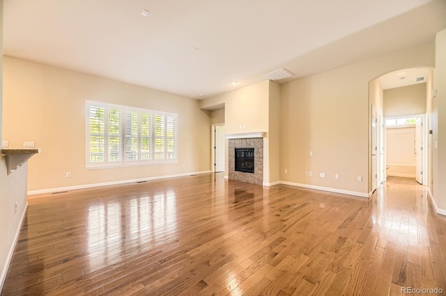 16550 Antero Cir, Broomfield, CO 80023 - unfurnished living room with hardwood / wood-style flooring, arched walkways, and a tiled fireplace