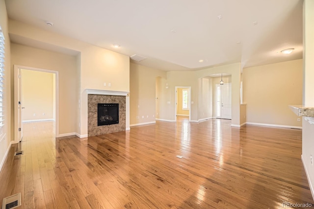 16550 Antero Cir, Broomfield, CO 80023 - unfurnished living room featuring arched walkways, light wood-style floors, a fireplace, and recessed lighting