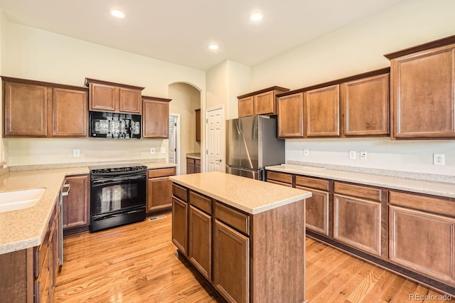 16550 Antero Cir, Broomfield, CO 80023 - kitchen with black appliances, arched walkways, light wood-style flooring, a center island, and recessed lighting