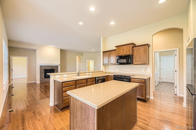 16550 Antero Cir, Broomfield, CO 80023 - kitchen with black appliances, a peninsula, brown cabinets, light wood-type flooring, and a center island