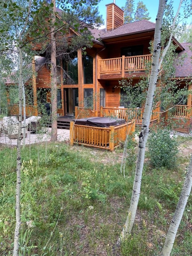 exterior space featuring a hot tub and a balcony