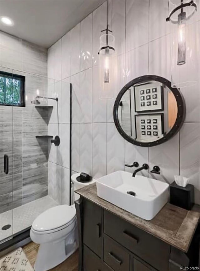 full bathroom with toilet, wood finished floors, vanity, tile walls, and a shower stall