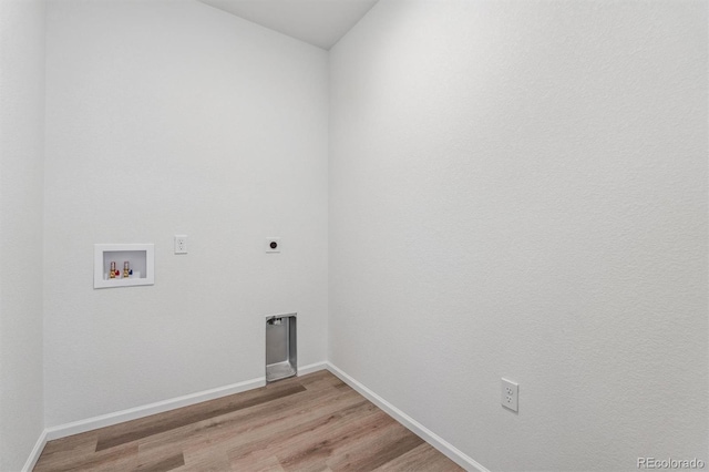 clothes washing area with hookup for an electric dryer, laundry area, washer hookup, baseboards, and light wood-style floors