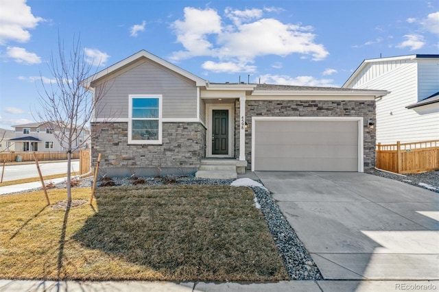 ranch-style house featuring concrete driveway, stone siding, an attached garage, fence, and a front lawn