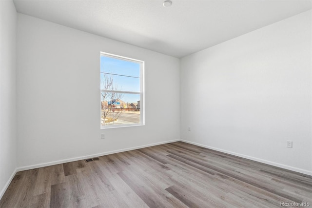 spare room with baseboards, visible vents, and light wood-style floors