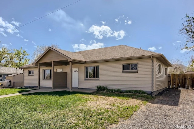 ranch-style house with roof with shingles, a front yard, and fence