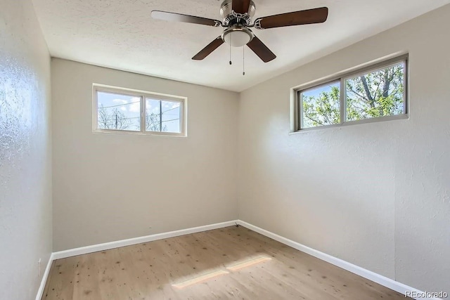 empty room featuring baseboards, ceiling fan, wood finished floors, and a healthy amount of sunlight