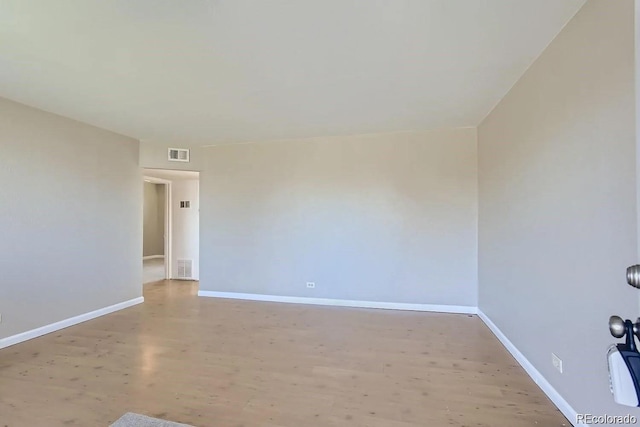 empty room with light wood-style floors, visible vents, and baseboards