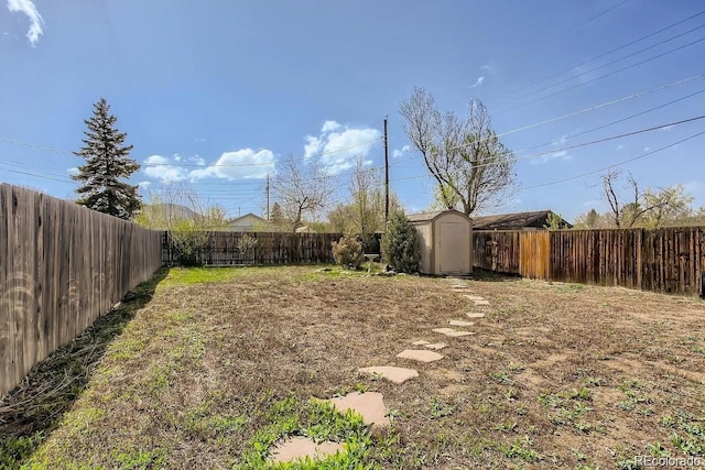 view of yard with an outbuilding, a fenced backyard, and a shed