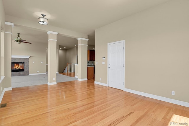 1975 Wild Star Way, Castle Rock, CO 80104 - unfurnished living room featuring a ceiling fan, decorative columns, light wood-style floors, a fireplace, and baseboards