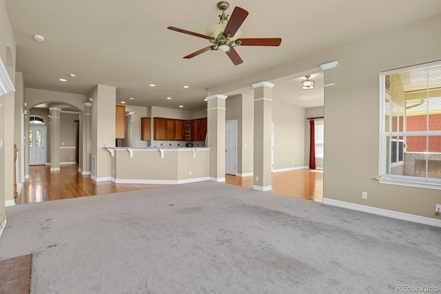 1975 Wild Star Way, Castle Rock, CO 80104 - unfurnished living room featuring light colored carpet, decorative columns, ceiling fan, arched walkways, and recessed lighting