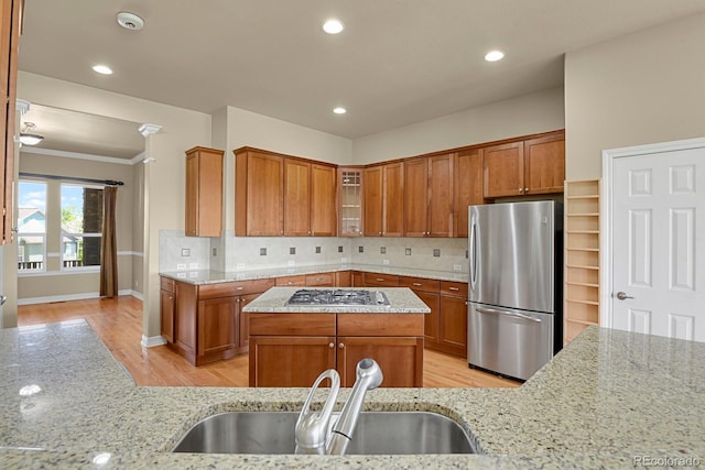 1975 Wild Star Way, Castle Rock, CO 80104 - kitchen with stainless steel appliances, a sink, light wood-style floors, brown cabinets, and light stone countertops