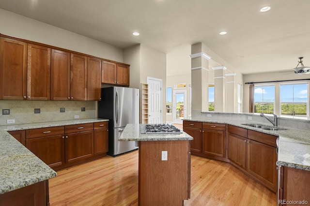 1975 Wild Star Way, Castle Rock, CO 80104 - kitchen featuring stainless steel appliances, a sink, light wood finished floors, light stone counters, and a center island