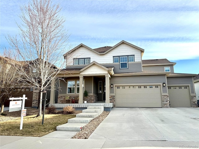 view of front of house featuring stone siding, covered porch, and concrete driveway