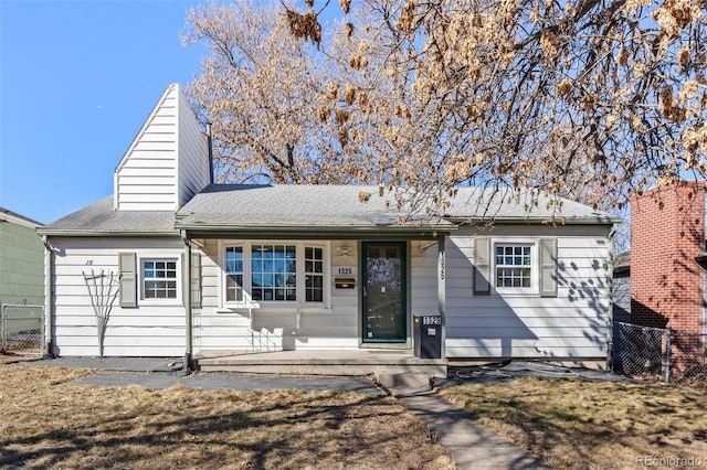 ranch-style house featuring a shingled roof and fence