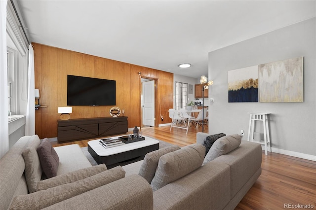 living room featuring wooden walls, baseboards, and wood finished floors