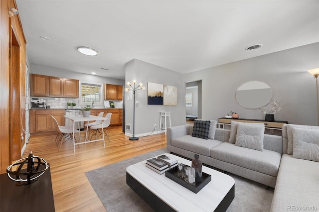 living area featuring light wood-style floors, baseboards, and visible vents