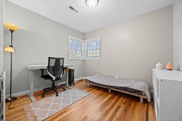 bedroom featuring baseboards, visible vents, and wood finished floors