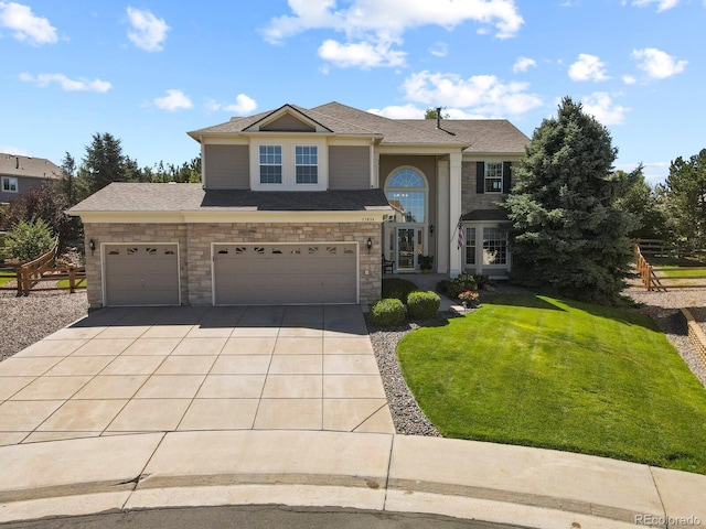 traditional-style house with stone siding, concrete driveway, and a front lawn