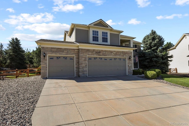 view of front of property featuring stone siding, driveway, an attached garage, and fence