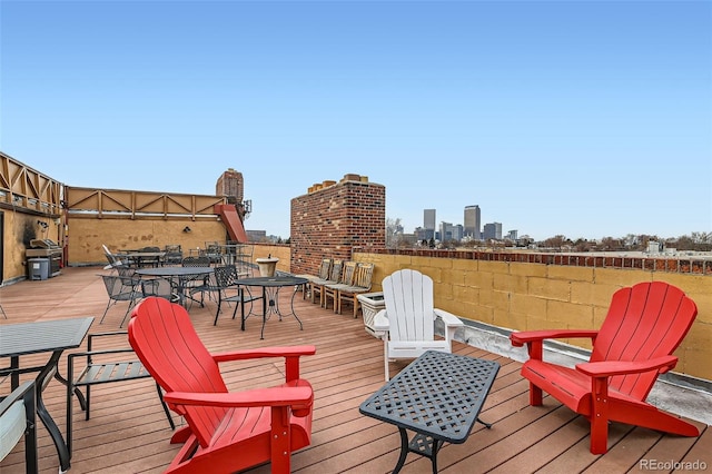 wooden deck featuring outdoor dining area, a view of city, and a grill