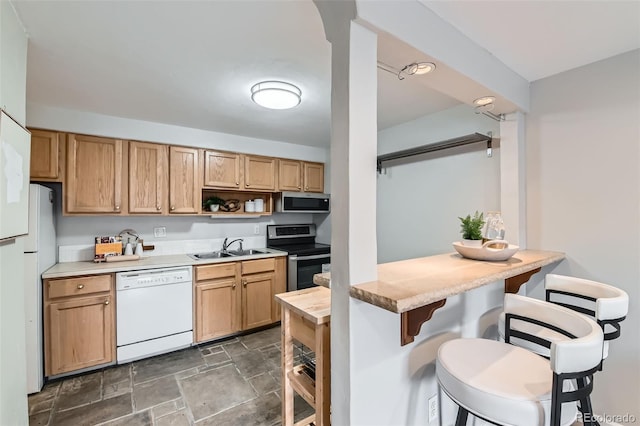 kitchen featuring a sink, a breakfast bar, appliances with stainless steel finishes, stone finish floor, and open shelves